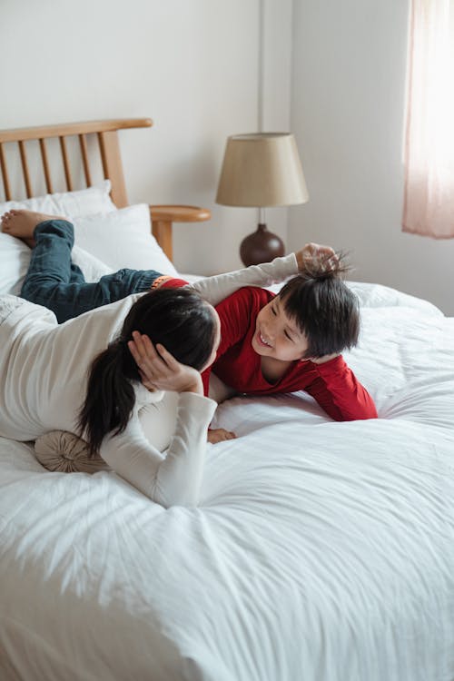 Photo of Mother and Son Lying Down on Bed