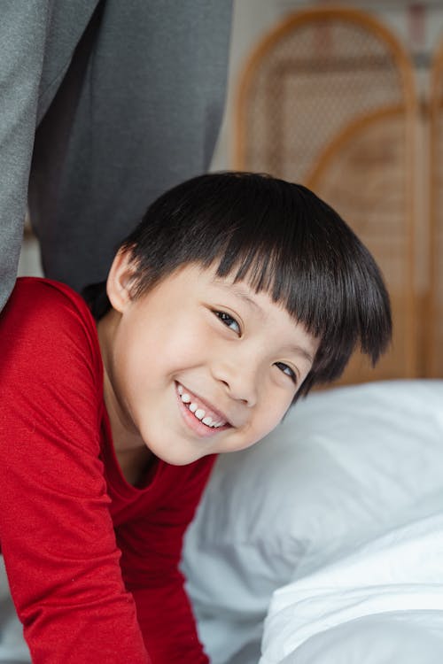 Cheerful little boy playing on bed