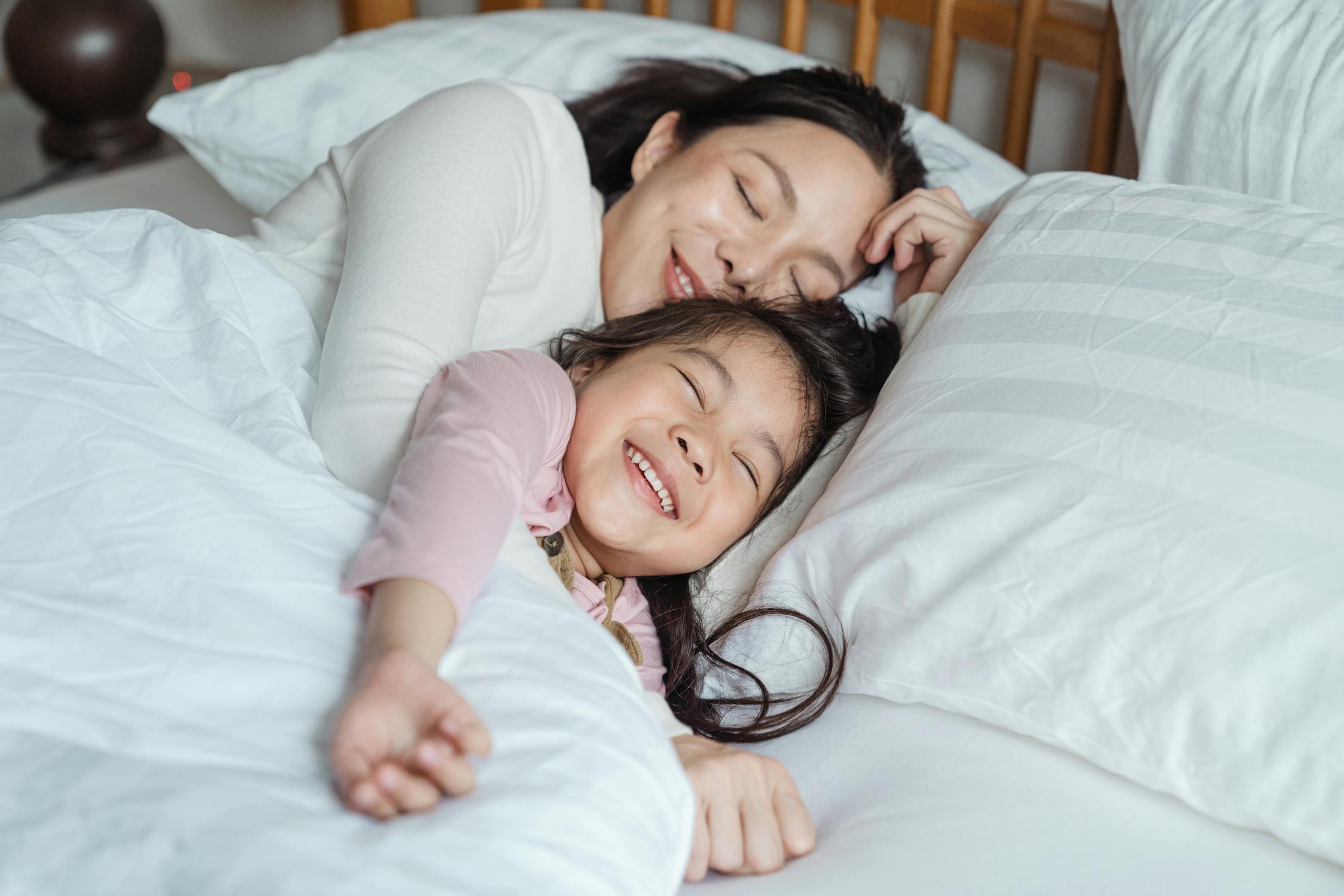 Cheerful mother and daughter resting in bed