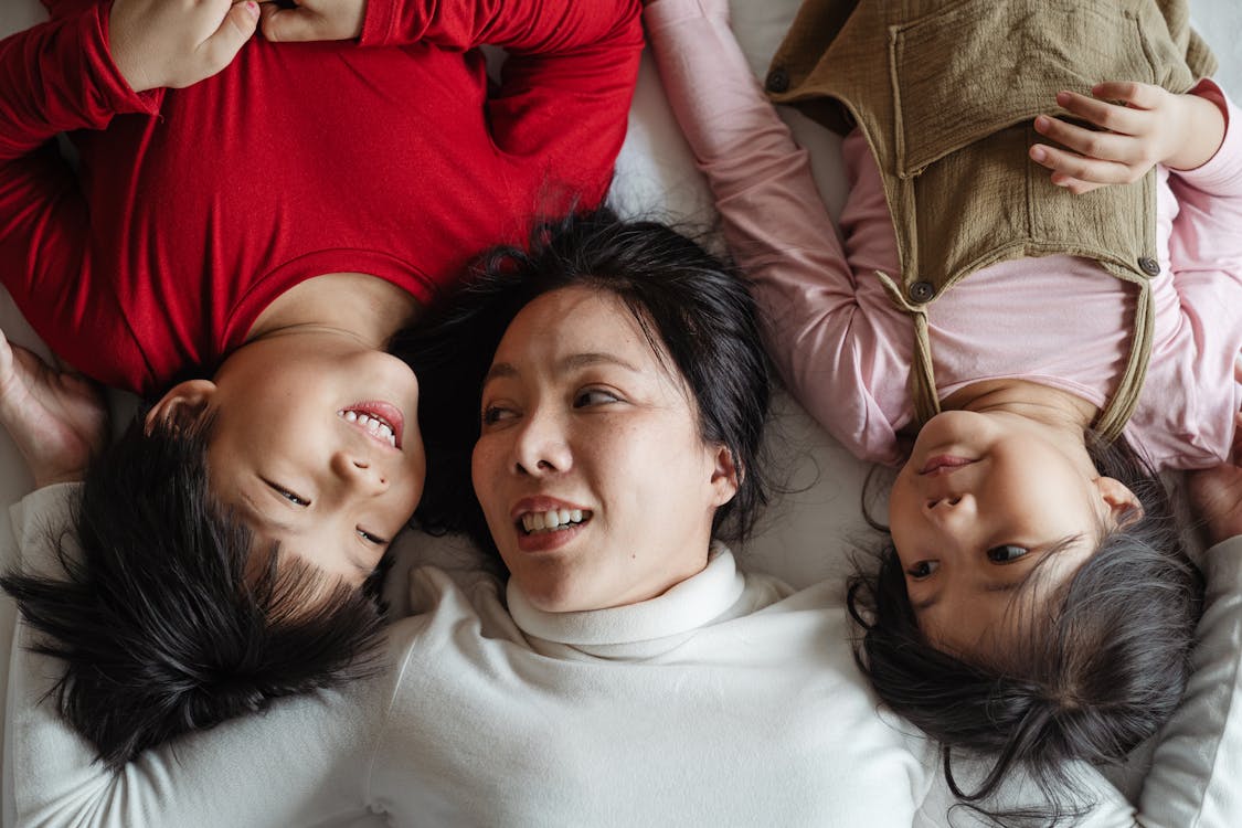 Photo of Woman and Her Children Lying on Bed