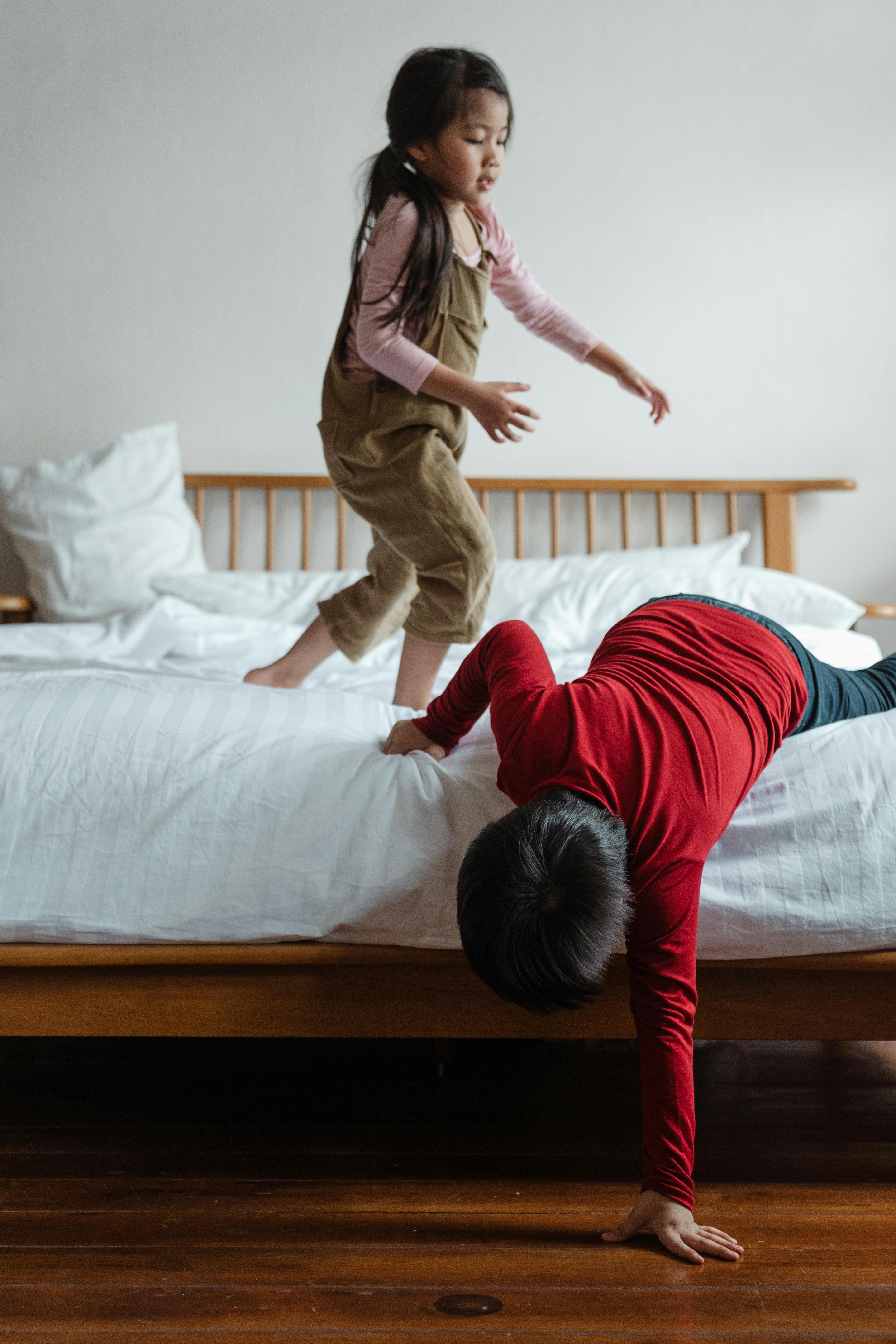 happy little siblings playing on bed