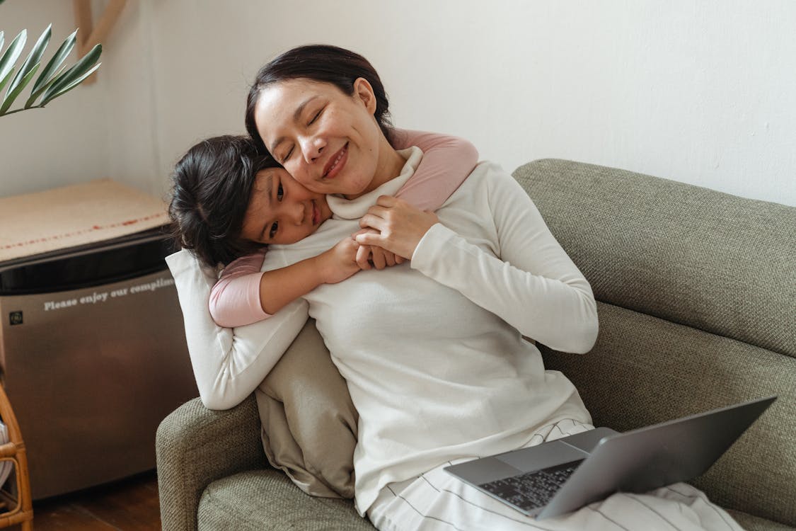Happy mother and daughter hugging on sofa