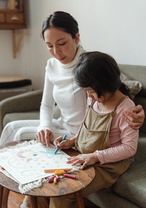 Focused mother and daughter drawing on paper