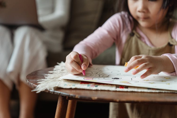 Crop Girl Coloring Drawing With Wax Pencils At Coffee Table