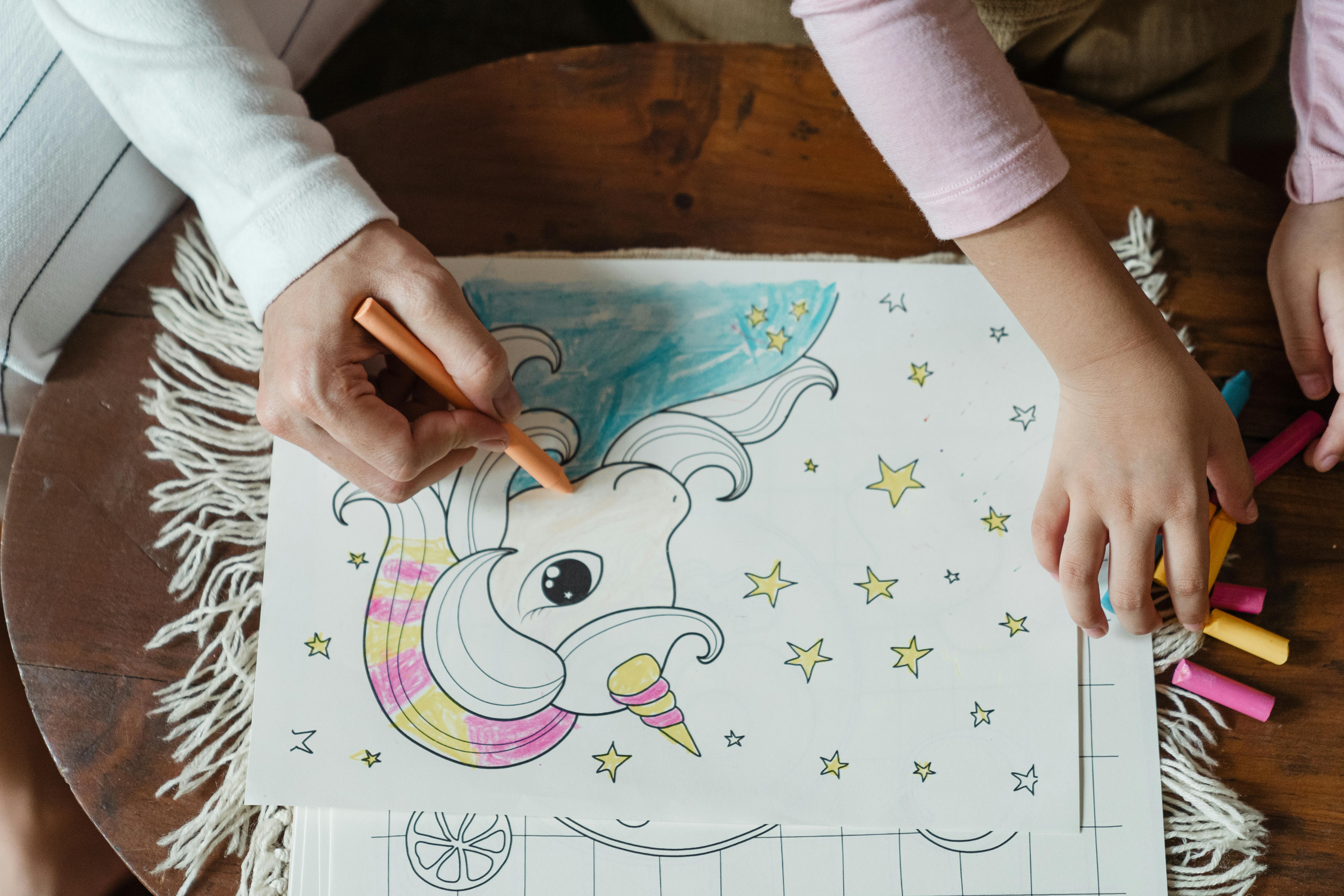 crop woman and daughter coloring drawing with wax pencils