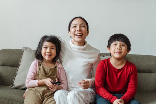 Free Interested Asian children with mother watching movie on TV channel Stock Photo