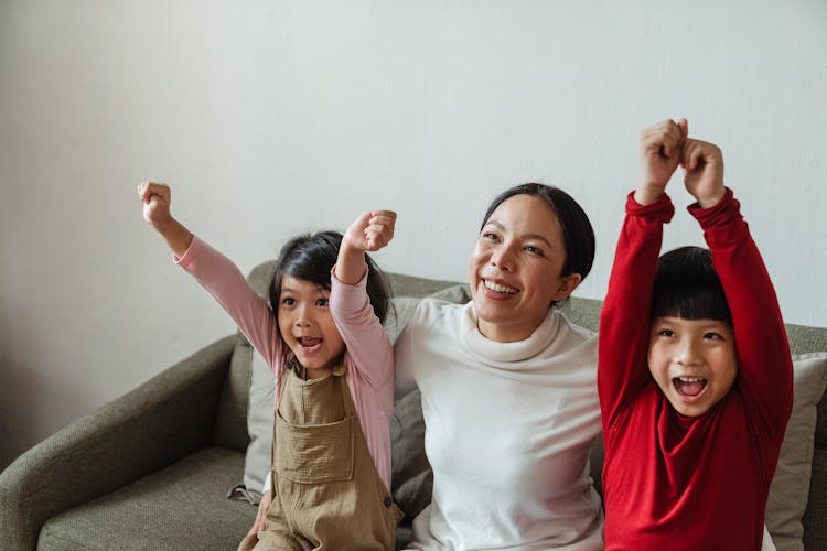 Happy Asian Woman With Kids Cheering While Watching TV