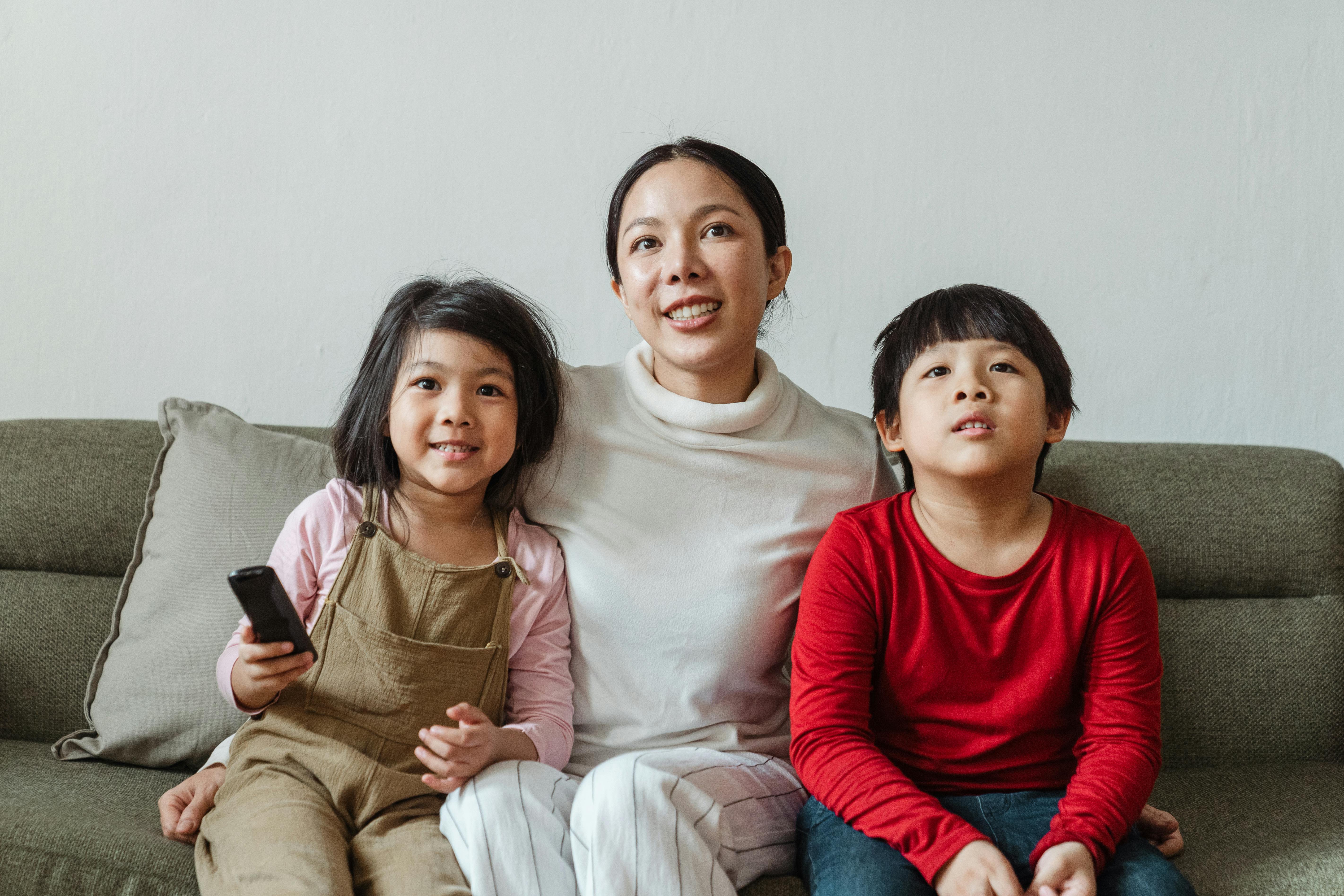 positive mother with daughter and son watching cartoon on tv