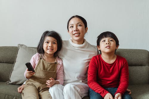 Positive mother with daughter and son watching cartoon on TV