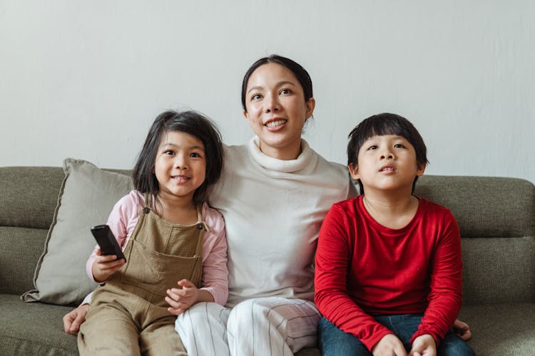 Positive Mother With Daughter And Son Watching Cartoon On TV