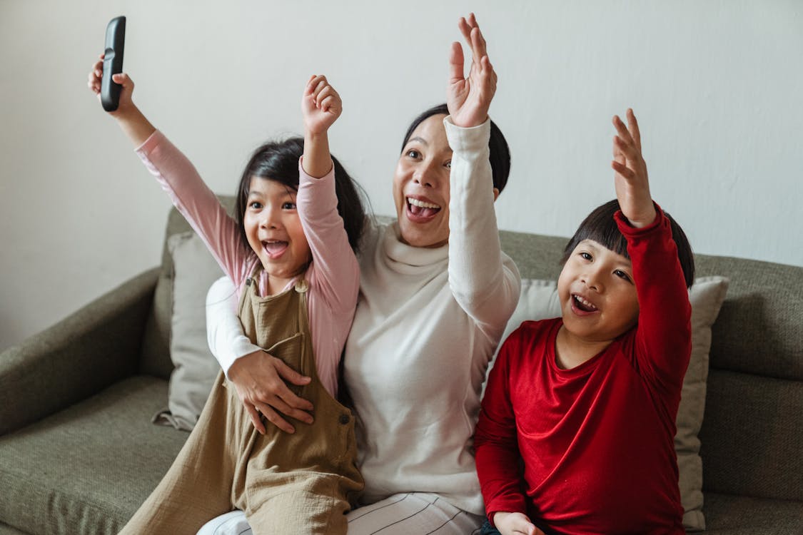 Free Positive ethnic mother with children watching football on TV and celebrating goal Stock Photo