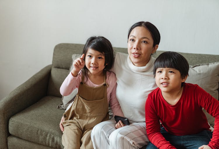 Adorable Little Asian Children Watching Fascinating Movie With Mom