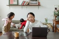 Tired ethnic working mother at home with playing kids