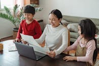 Cute ethnic kids showing pictures to cheerful mom