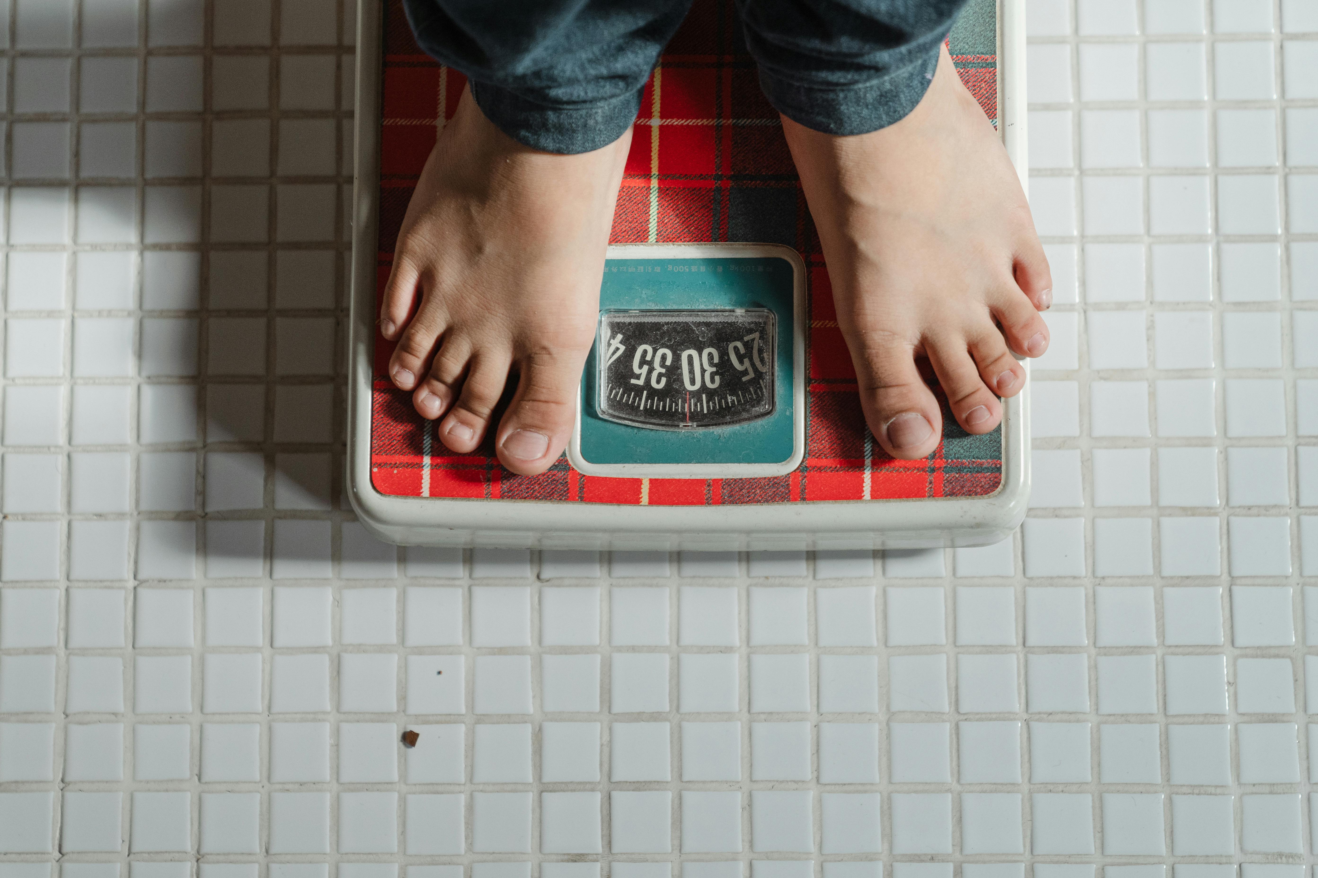 A person weighing on scale. | Photo: Pexels