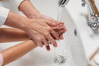 Crop mother washing hands of kid in washbasin