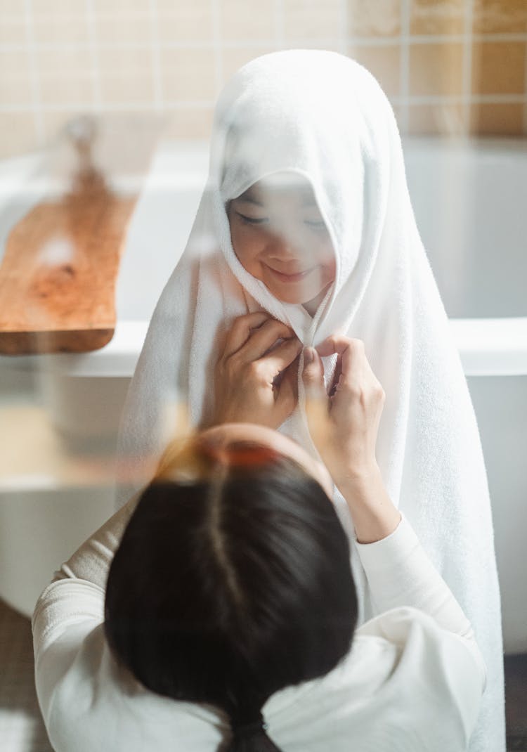 Caring Mother Drying Child With Towel In Bathroom