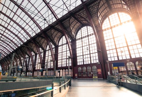 Free Interior of a bright, arched train station with sunlit windows in Europe. Stock Photo