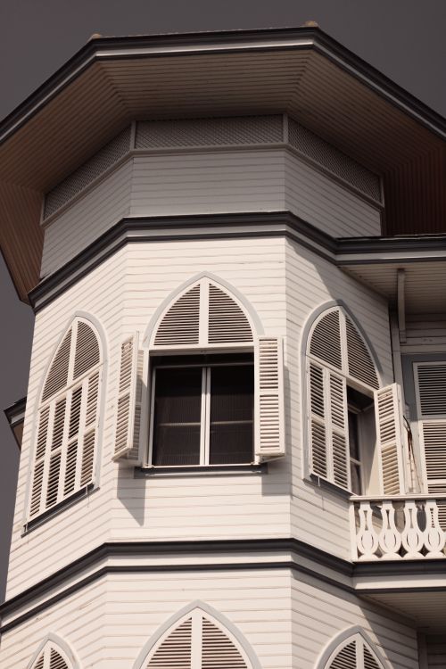 Free A close-up view of a vintage tower with open shuttered windows, showcasing elegant architectural details. Stock Photo