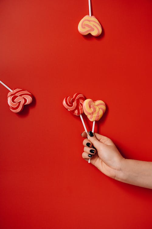 Person Holding Red Heart Shaped Lollipops