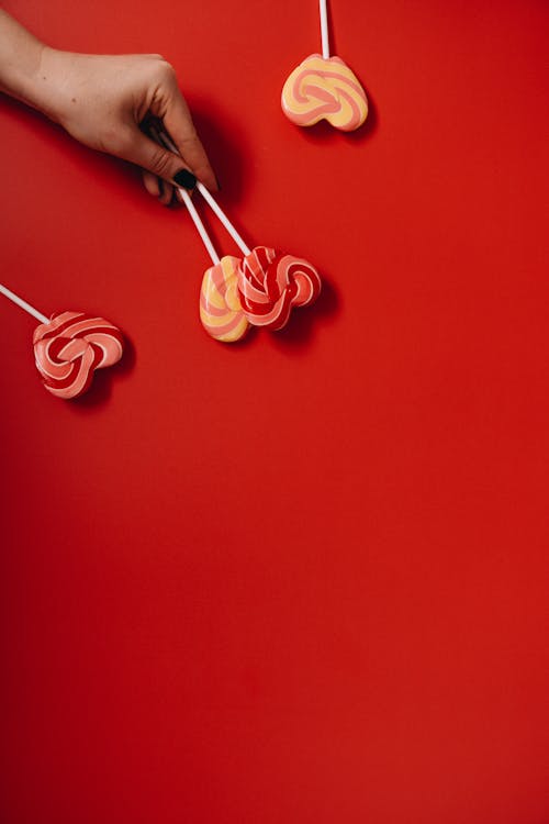 Photo of Person Holding Heart Shaped Lollipops