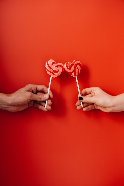 Free Two Hands Holding Heart Shaped Lollipops Stock Photo