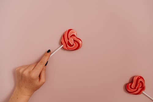 Person Holding Red Heart Shaped Lollipop