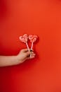 手握心形棒棒糖，背景鲜艳的红色象征着爱情