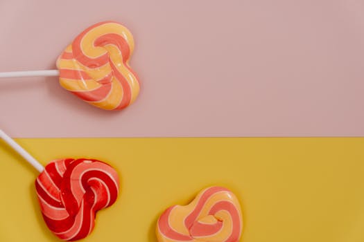 Vibrant heart-shaped lollipops on a pastel background, perfect for sweet-themed projects.