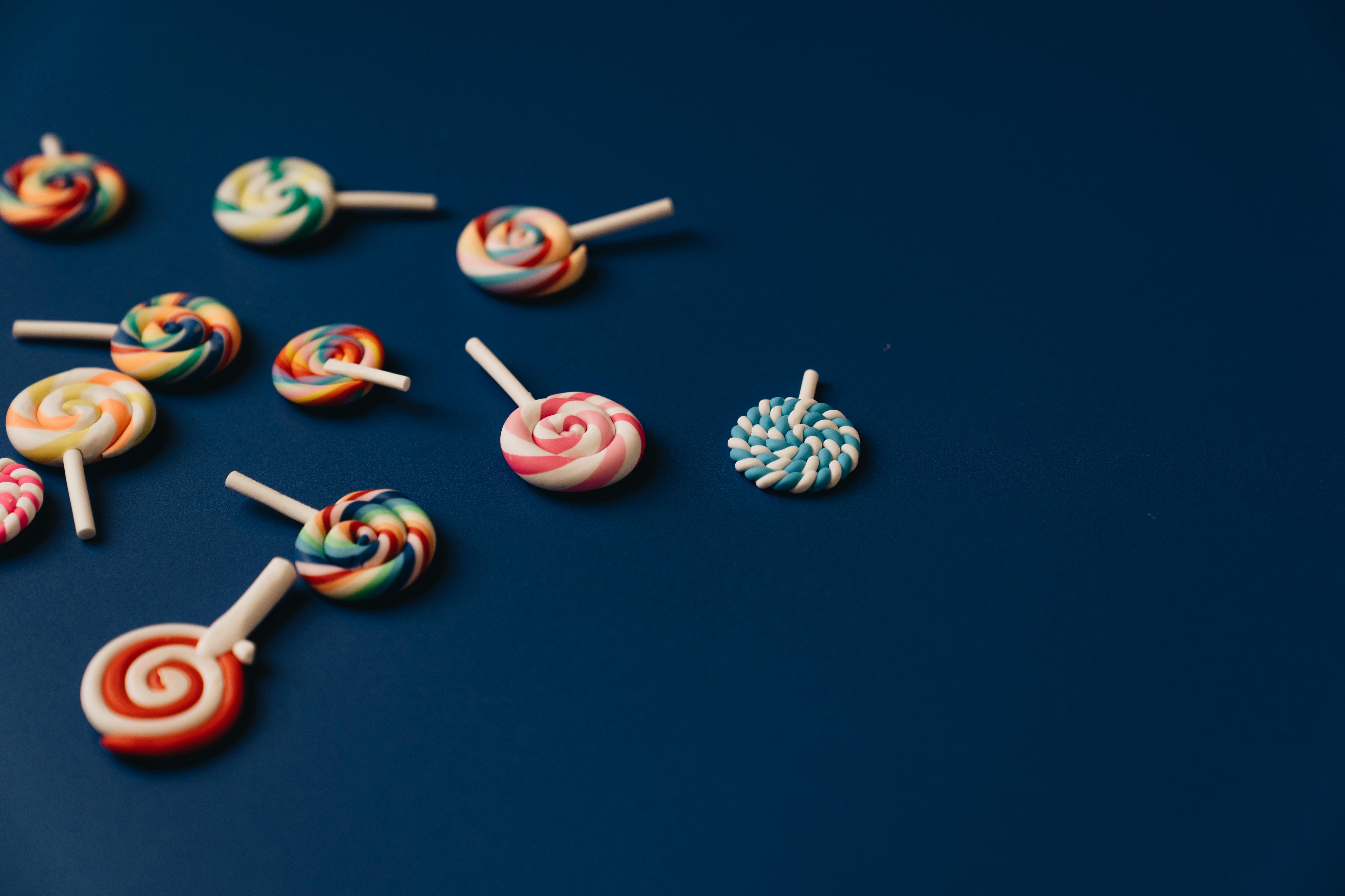 Brightly colored lollipops scattered on a blue background, offering ample copy space.