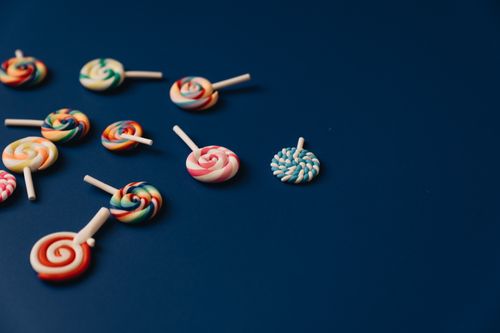 Free Brightly colored lollipops scattered on a blue background, offering ample copy space. Stock Photo