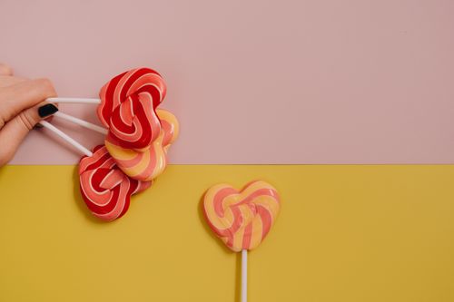 Free Brightly colored heart-shaped lollipops on a vibrant pastel background with copy space. Stock Photo