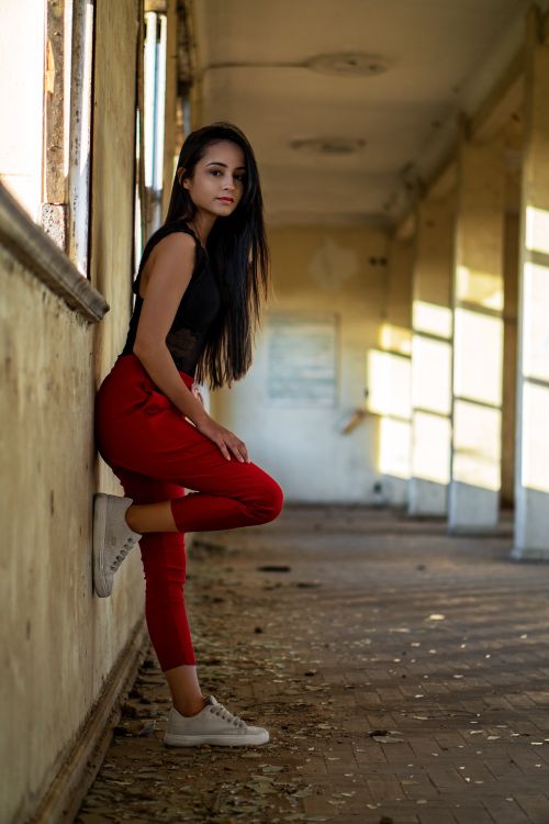 Free Side view of carefree ethnic female millennial leaning on wall of abandoned building and looking at camera Stock Photo