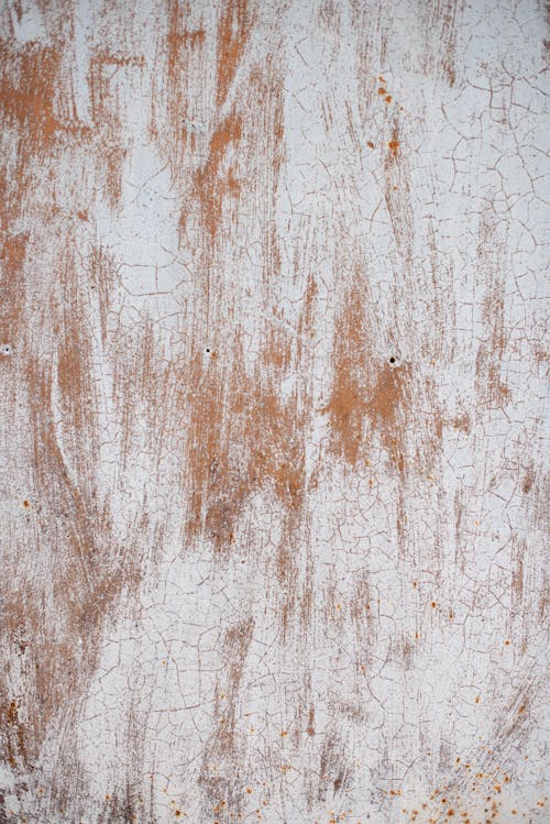 Rough textured background of weathered metal wall of aged building painted in white