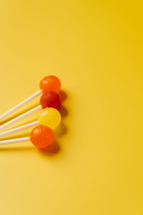 Free Bright and colorful lollipops arranged on a yellow background, ideal for candy themes. Stock Photo
