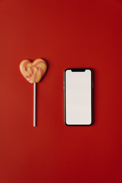 Smartphone and Lollipop on Red Background