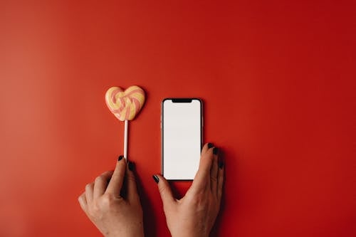 Lollipop and Smart Phone on Red Background 