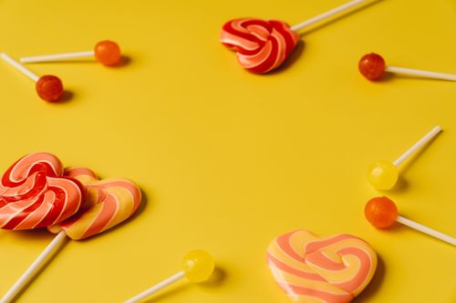 Free Assorted lollipops arranged creatively on a yellow background with copy space. Stock Photo
