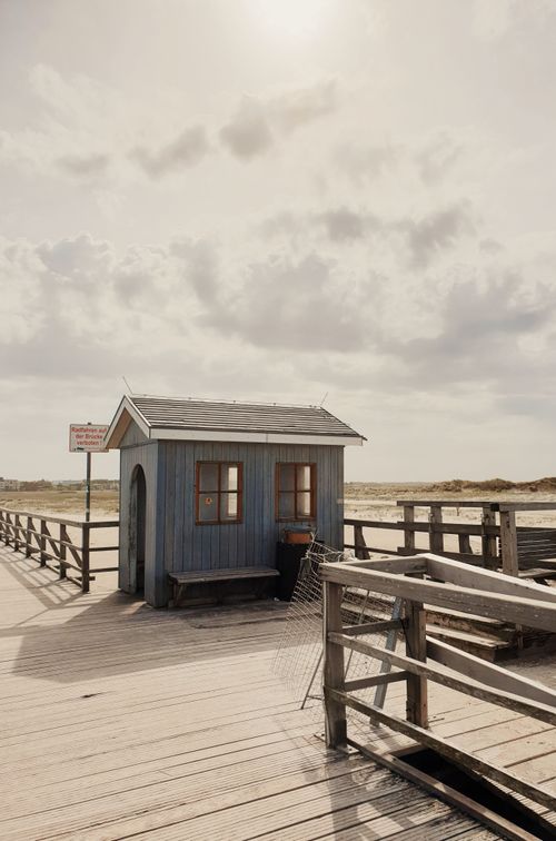 Free Old wooden house located on lumber promenade along sandy beach on sunny day Stock Photo