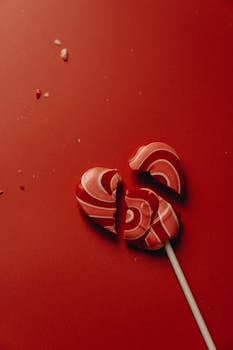 红底破碎的心形棒棒糖象征着爱情与心碎