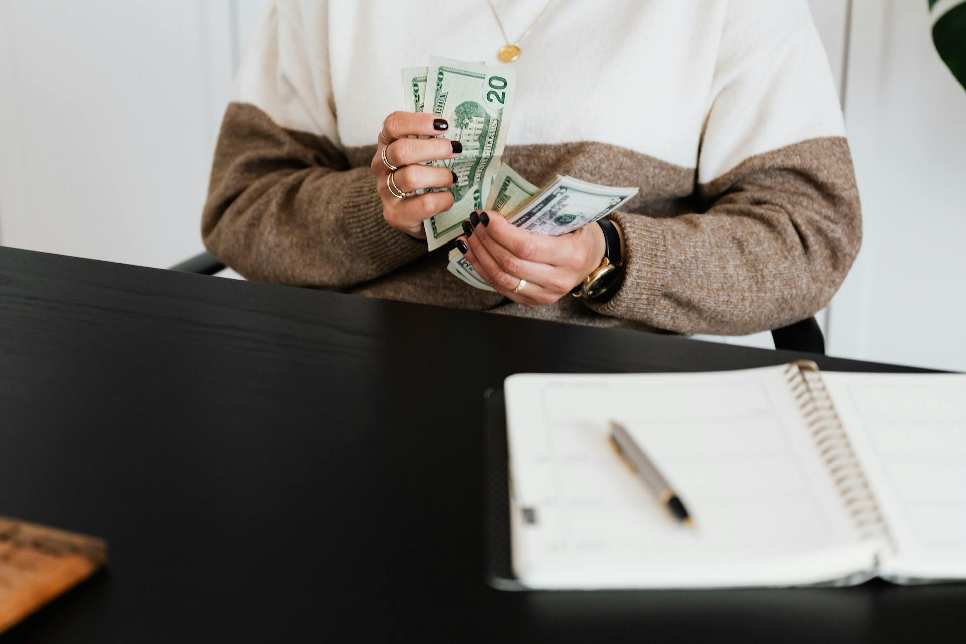 A Person in Sweater Counting Her Money