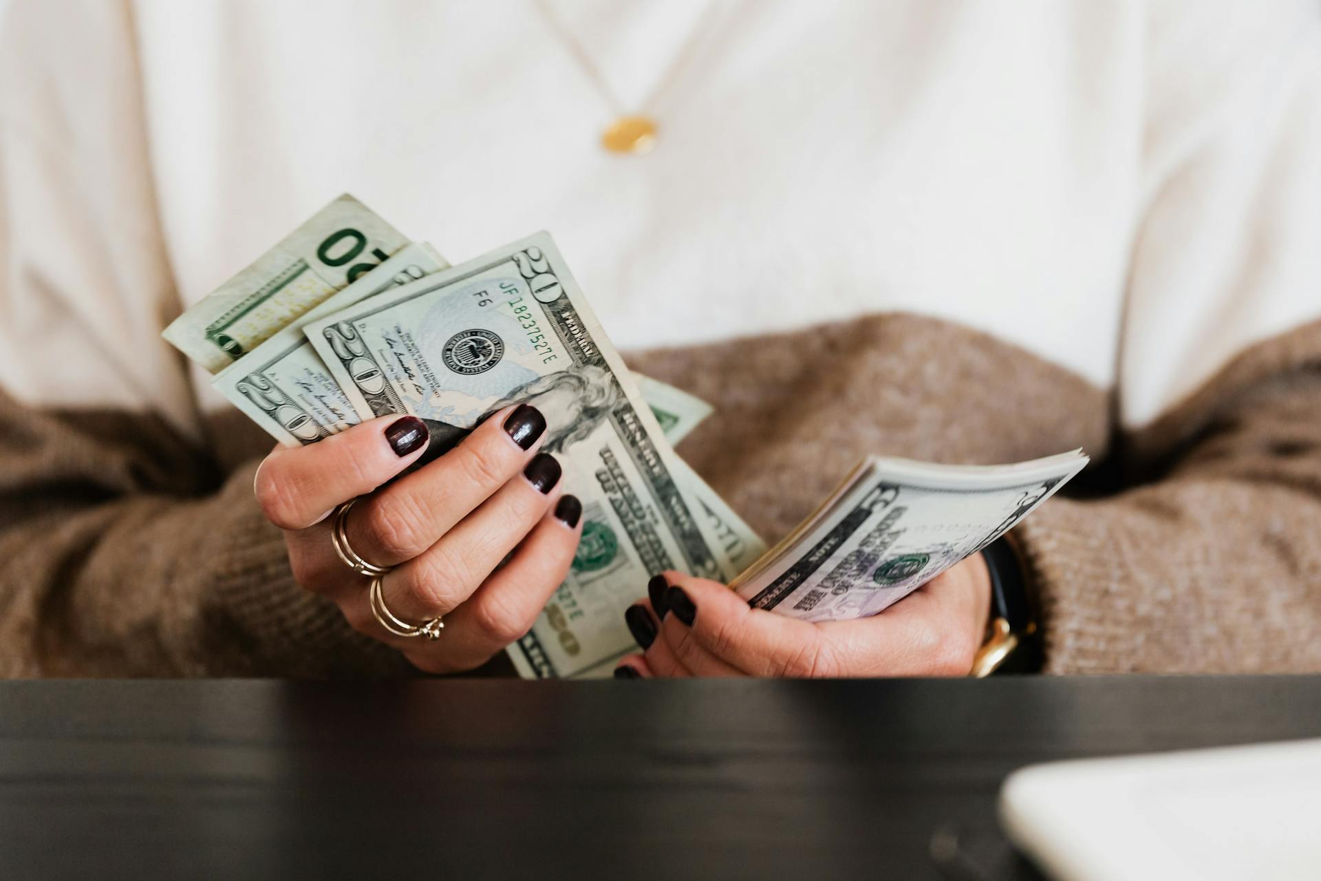 Close-up of hands counting US dollar bills, depicting finance and money handling.