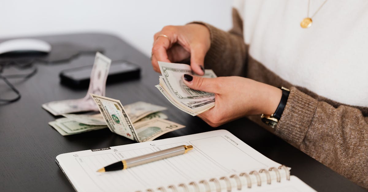 Closeup of person counting cash with notepad on desk, indicating financial tasks