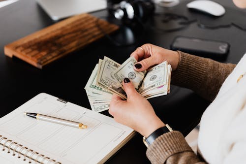 Crop woman counting money at modern office table