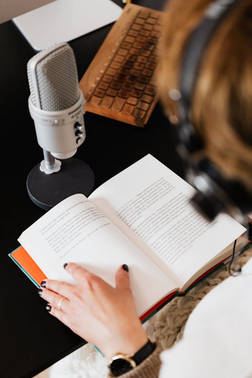 Free High angle of elegant female audiobook narrator recording audiobook while sitting at desk with microphone Stock Photo
