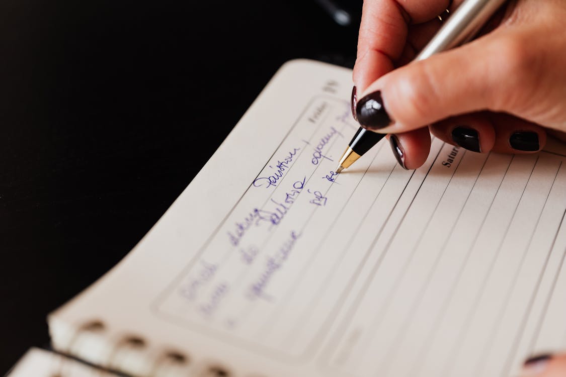 Crop woman writing in notebook