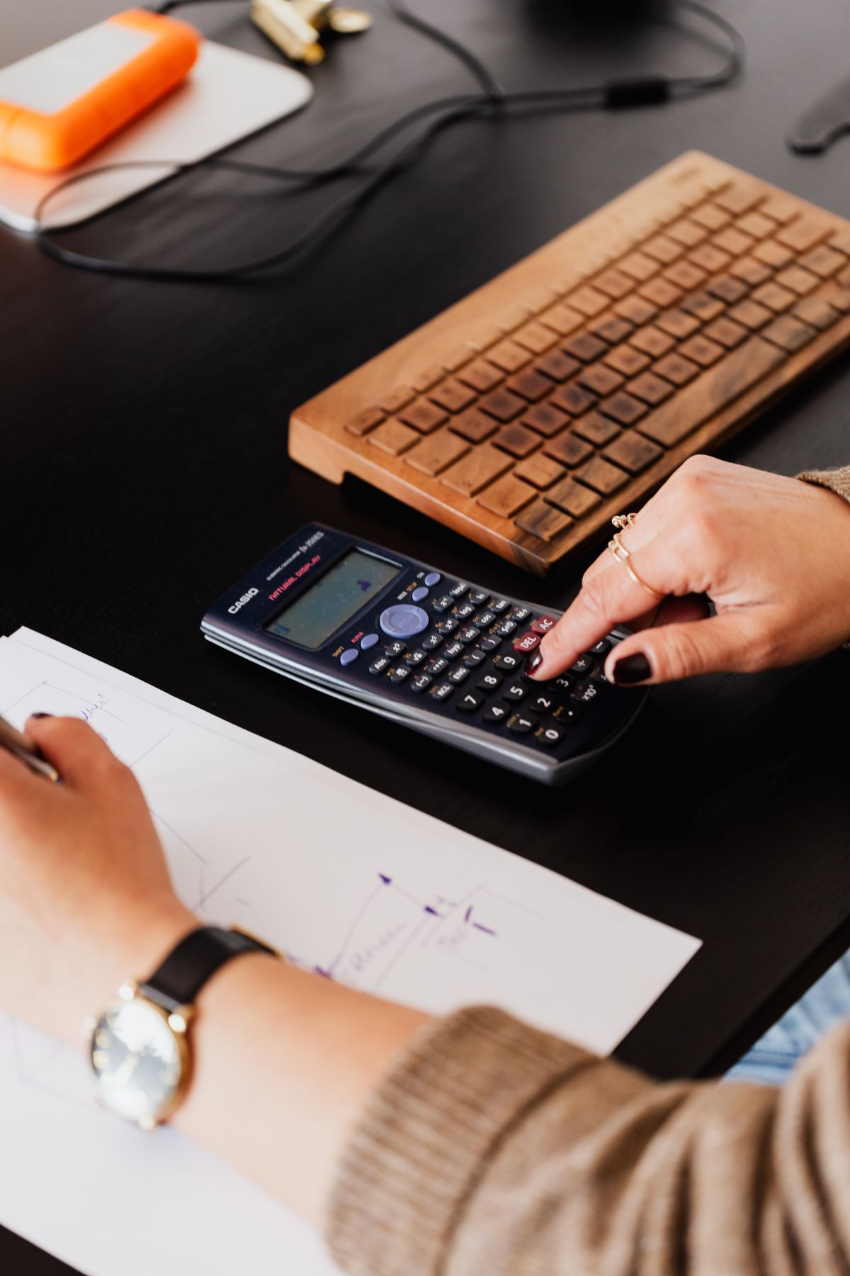 Professionnel utilisant une calculatrice entouré de documents
