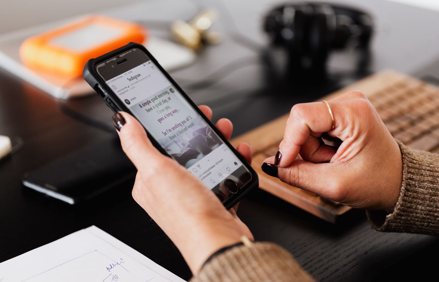 A woman checks social media notifications on her smartphone in an office setting.