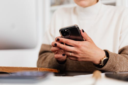 Crop woman browsing smartphone at table