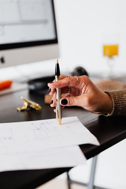 Crop woman with pen near computer